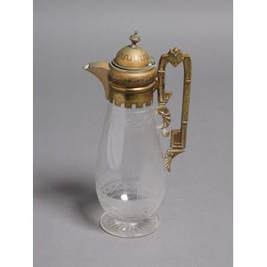 A claret jug with metal mounts, engraved with a cricketing…