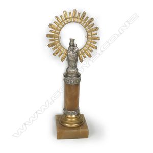 A small silvered metal religious votive figure, Mary holding…
