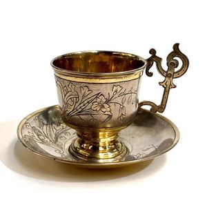 A silver metal demitasse cup & saucer, engraved detail with…