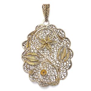 A silver metal filigree pendant with floral motifs with…