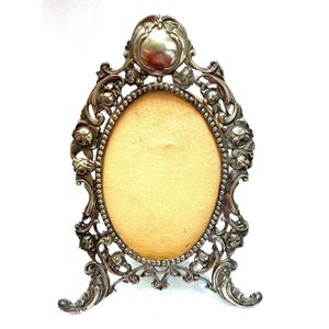 A silver metal oval filigree frame with unverified Russian…