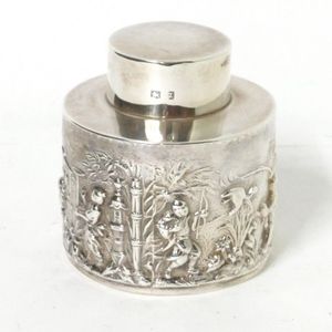 A small silver tea caddy, cylindrical, decorated in relief with…