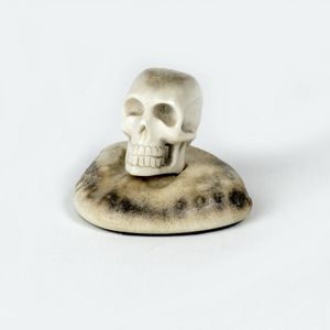 A small antler carving, in the form of a skull, attached to an…