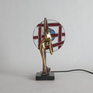 An Art Deco lamp., features a woman holding a circle frame with…