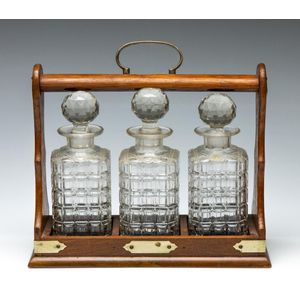 An oak framed tantalus with three glass decanters and brass…