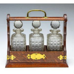 An oak three bottle tantalus, width 33 cm comes with key,