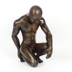 A bronze sculpture of a young man, modelled crouching on one…