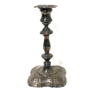 A silver candlestick square shaped base supporting a slender…