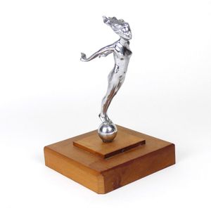 A vintage car mascot of a chromed naked woman, standing upon a…