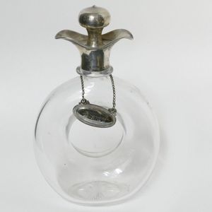 An Edwardian silver mounted glass annular ring decanter, the…