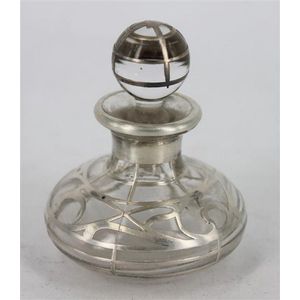A glass perfume bottle with silver overlay, swirling pattern.