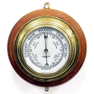 An antique circular brass English aneroid barometer with oak…