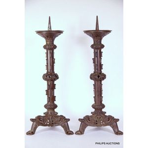 A pair of large German pricket candlesticks, circa 1600 Brass candle  holders cast in one piece. Tiered bell-shaped feet, the stems segmented by  balusters and widely drip-pans. Forged, iron prickets on riveted