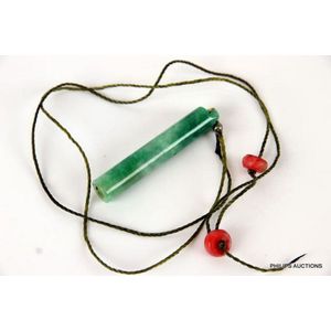 A jade cylindrical pendant, a pale green stone with darker…