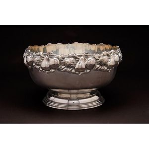 A large silver-plated shallow wine cooler decorated to the rim…