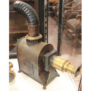 An antique tin movie projector, 45 cm high, 36 cm wide.