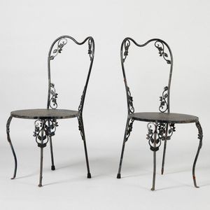 A pair of black painted outdoor chairs, in steel with foliate…