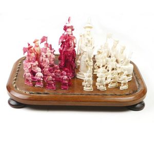 A Chinese ivory chess set, mounted on a board under a glass…
