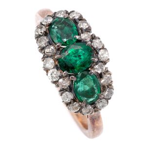 An emerald and diamond ring, set across the top with 3 oval cut…