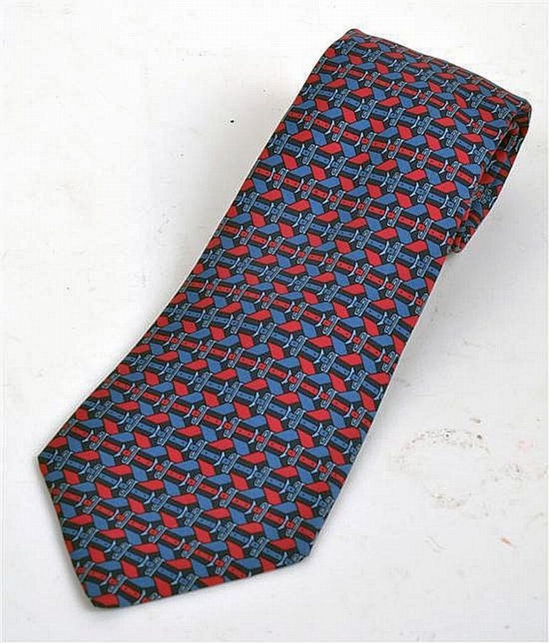 A silk tie by Hermes styled with a red and blue buckle design ...