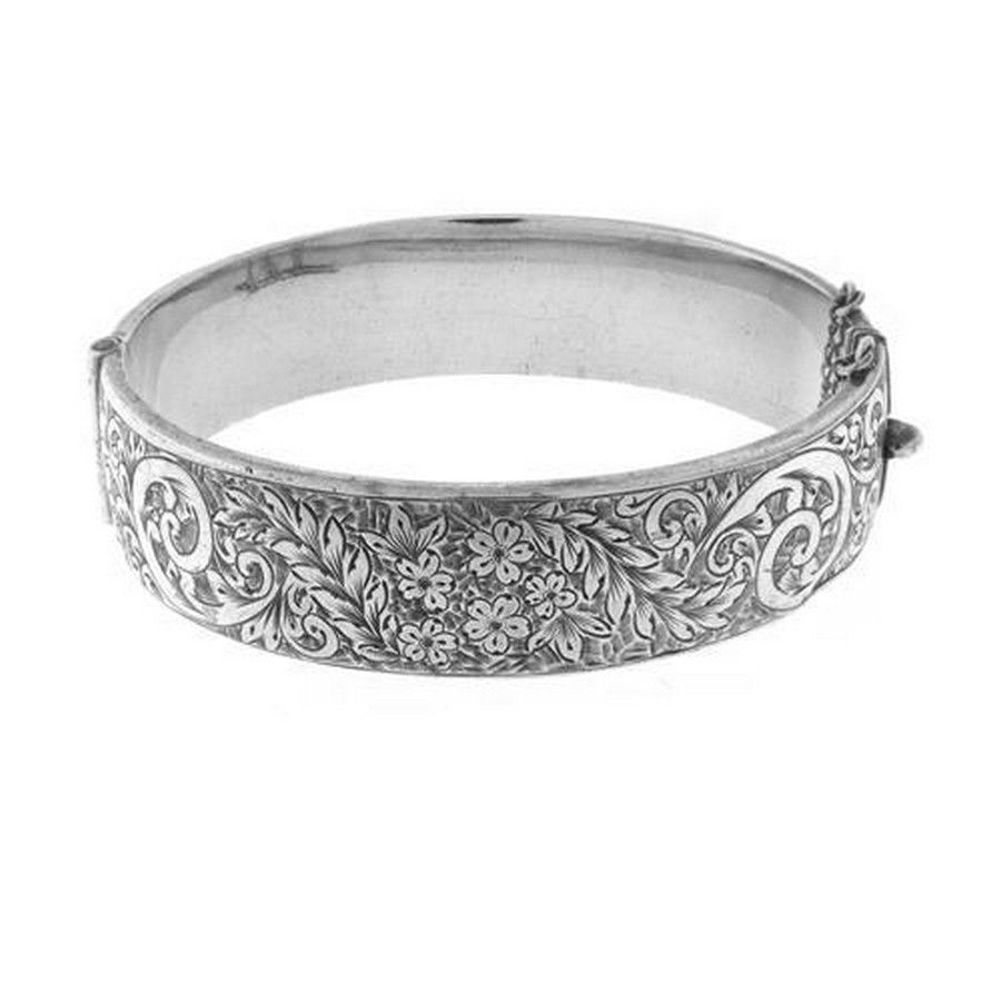 A vintage silver hinged bangle, front engraved with flowers and ...